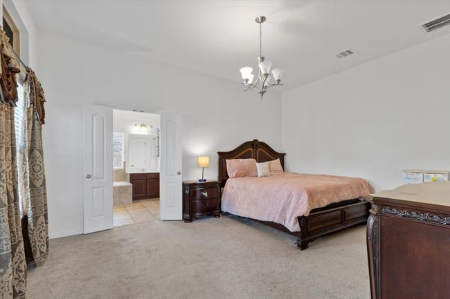 Bedroom featuring light carpet, ensuite bathroom, visible vents, and a chandelier | Image 14