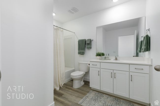 Bathroom with shower / bathtub combination with curtain, vanity, toilet, visible vents, and wood finished floors | Image 31