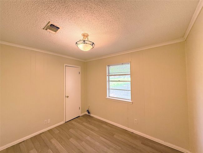 Spare room featuring wood finished floors, a textured ceiling, and ornamental molding | Image 18