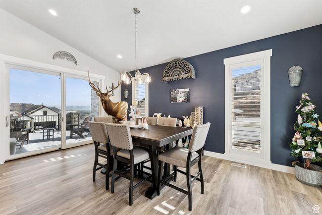 Dining room featuring light wood finished floors, an inviting chandelier, vaulted ceiling, and visible vents | Image 40