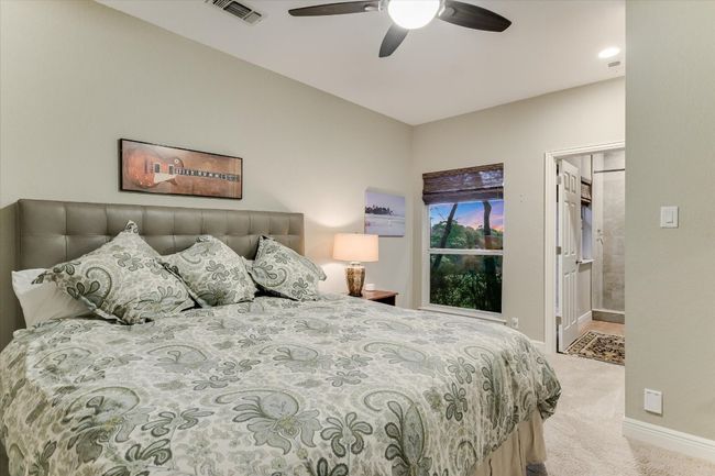 Bedroom featuring connected bathroom, ceiling fan, baseboards, and light colored carpet | Image 15