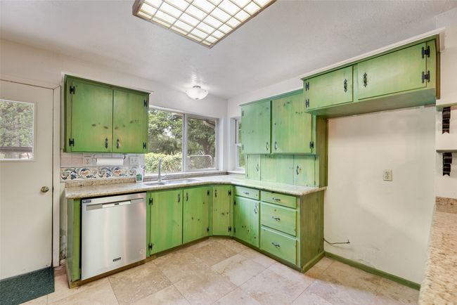 Kitchen with stainless steel dishwasher, a sink, light countertops, and green cabinetry | Image 13