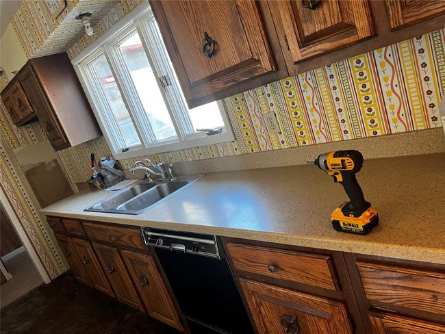 Kitchen with brown cabinetry, dishwasher, light countertops, and a sink | Image 67