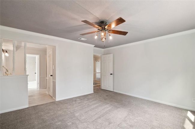 The well-appointed primary bedroom is located upstairs. It features crown molding and a classic ceiling fan. | Image 23