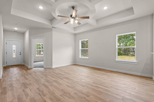 Bright and inviting livinf space featuring elegant coffered ceilings, recessed lighting, and an abundance of natural light from large windows. | Image 4