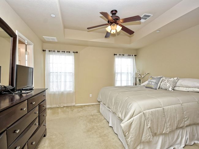 Bedroom with light carpet, visible vents, a raised ceiling, and multiple windows | Image 12