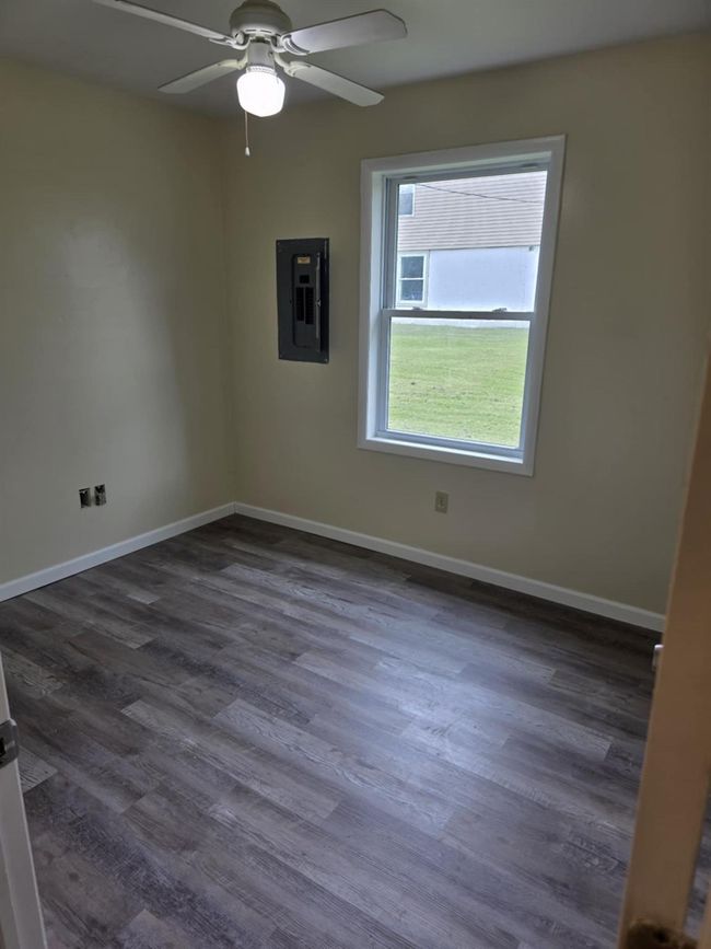 Spare room with dark wood-style floors, electric panel, and a ceiling fan | Image 18