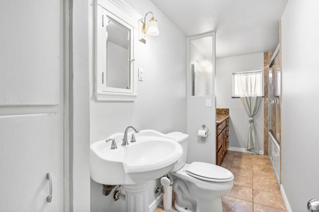 Full bath featuring shower / bath combination with glass door, toilet, and tile patterned flooring | Image 41