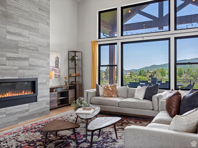 Living area featuring a fireplace, a high ceiling, a mountain view, and wood finished floors | Image 10