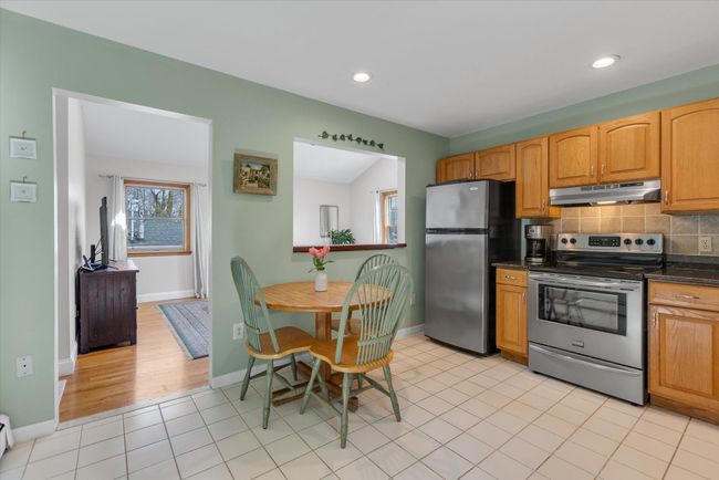 Eat in kitchen featuring stainless steel appliances, ample cabinet space, decorative backsplash, light tile flooring, and granite countertops | Image 4