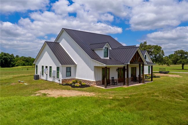 View of property exterior with a standing seam roof, metal roof, a yard, and board and batten siding | Image 38