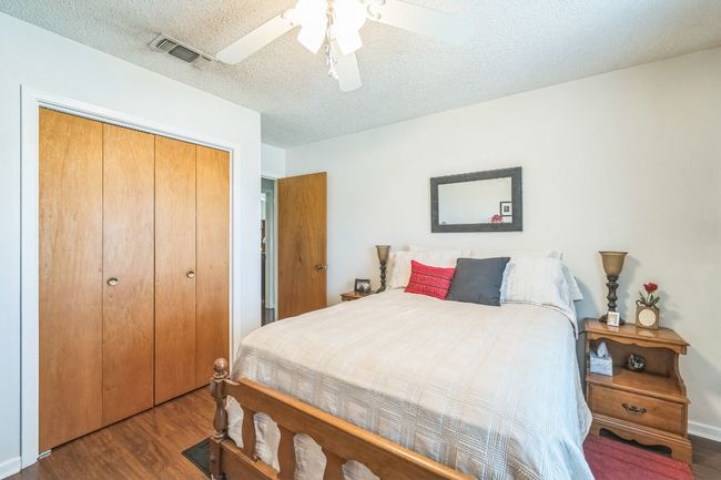 Bedroom with a closet, a textured ceiling, visible vents, ceiling fan, and wood finished floors | Image 21