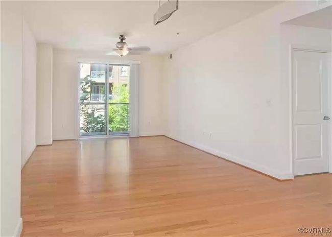 Empty room with wood finished floors, ceiling fan, and baseboards | Image 9