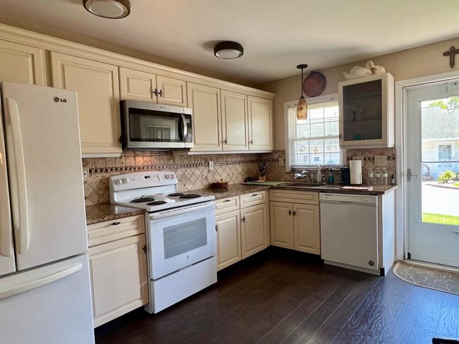 Kitchen with white appliances, healthy amount of natural light, tasteful backsplash, and dark wood finished floors | Image 4