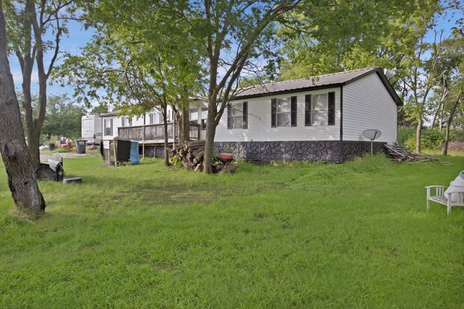 View of property exterior featuring a metal roof, a yard, and a wooden deck | Image 6