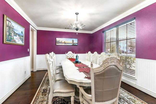 The formal dining room offers a convenient two-way entry, providing easy access to the kitchen through the Butler’s Pantry. While dining, you can enjoy pleasant views of the front yard through the large windows, creating a bright and inviting atmosphere. The space features the same beautiful wood flooring found throughout the home, adding continuity and warmth. A stunning chandelier hangs above, casting a soft glow over the room. With ample space for a large dining set, this room is perfect for hosting. | Image 12