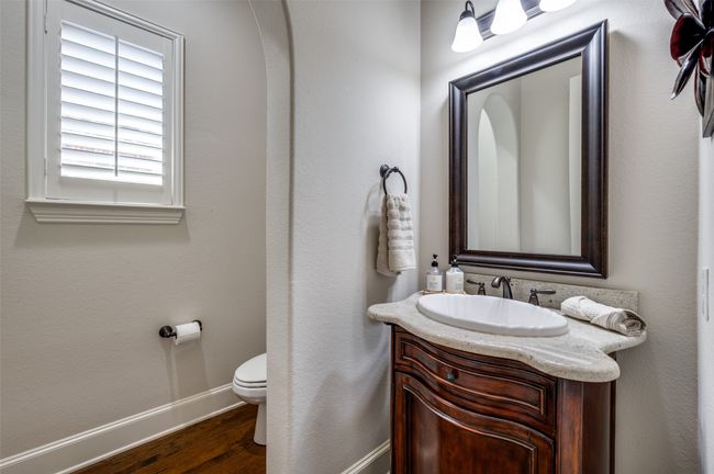 The first-floor half bath is perfect for guests, featuring a charming archway, an upgraded vanity, and a framed mirror for a touch of elegance. | Image 18