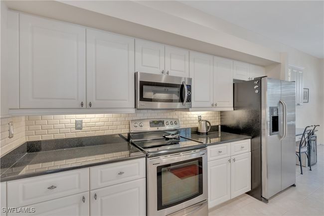 Kitchen featuring appliances with stainless steel finishes, dark countertops, tasteful backsplash, and white cabinets | Image 11