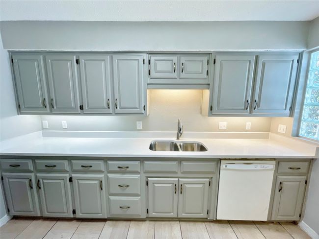 Kitchen with dishwasher, gray cabinets, a sink, and light countertops | Image 4