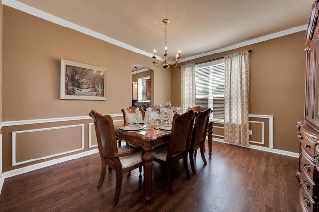 Dining space featuring a chandelier, arched walkways, ornamental molding, dark wood-style flooring, and wainscoting | Image 10