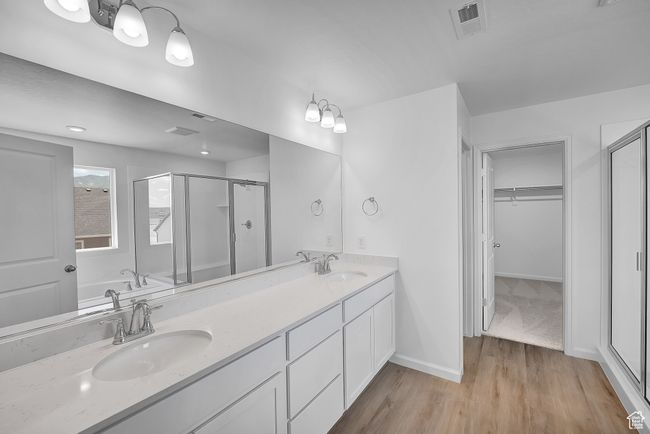 Full bathroom with a shower stall, a walk in closet, wood finished floors, double vanity, and a garden tub | Image 6