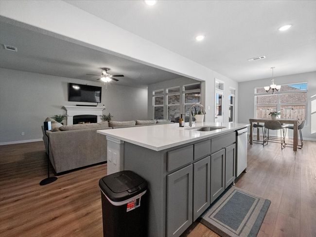 Kitchen with a center island with sink, light countertops, hanging light fixtures, a sink, and gray cabinets | Image 7