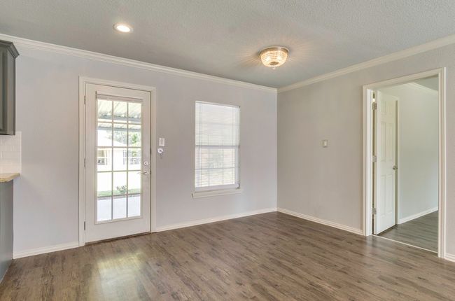 Unfurnished dining area with crown molding, dark wood-style flooring, and a textured ceiling | Image 10