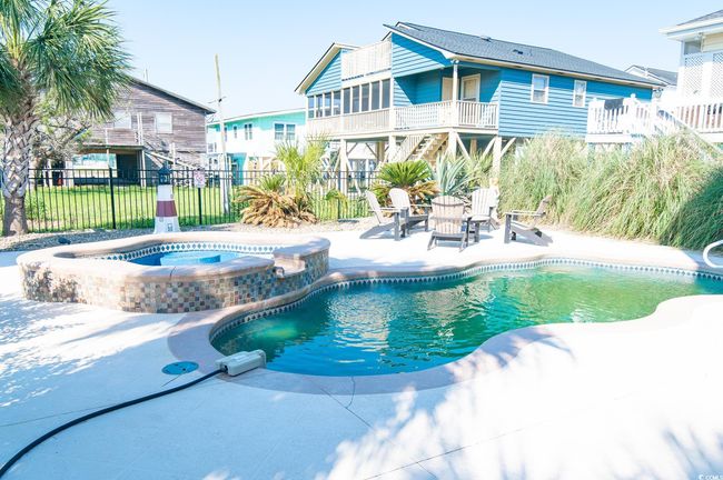 View of swimming pool with a patio area, fence, stairs, and a pool with connected hot tub | Image 12