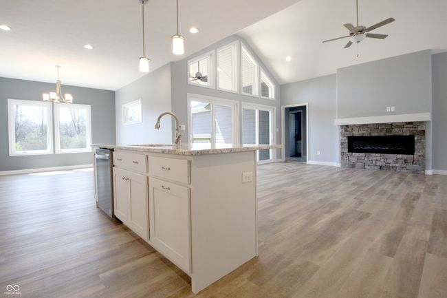 kitchen featuring a sink, open floor plan, light wood finished floors, white cabinetry, and ceiling fan with notable chandelier | Image 6
