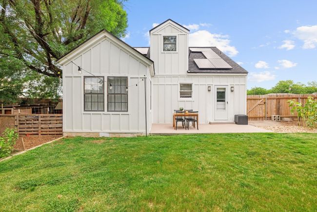 Back of house featuring board and batten siding, a patio area, a fenced backyard, and roof mounted solar panels | Image 25
