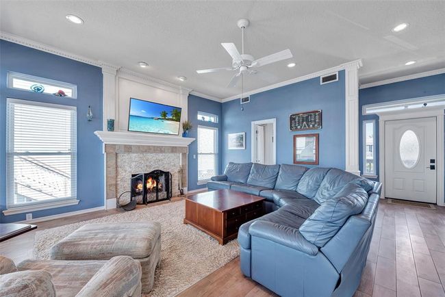 This inviting living area features soft recessed lighting, a beautifully tiled fireplace with a custom mantle, and space to gather or unwind. | Image 8