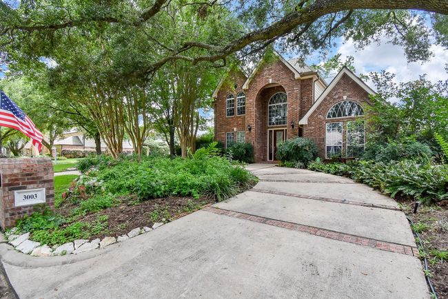 Charming brick home with a grand entrance, nestled within a lush, landscaped circular driveway. | Image 7