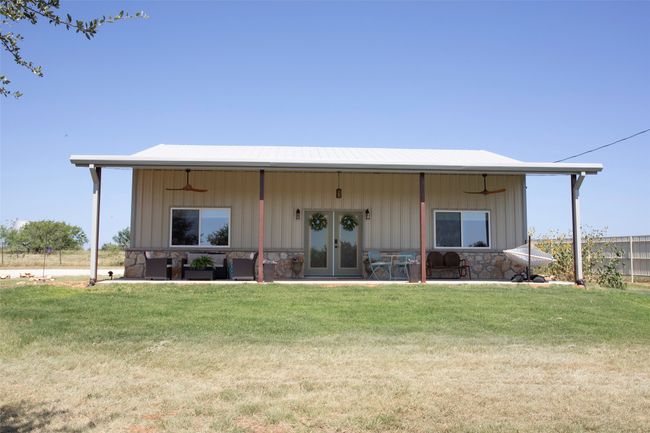 Back of property featuring a ceiling fan, board and batten siding, a lawn, a patio area, and french doors | Image 31