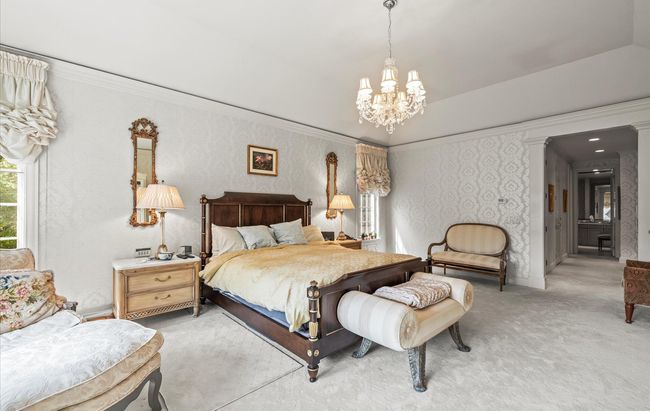 Carpeted bedroom featuring a chandelier, crown molding, and wallpapered walls | Image 19