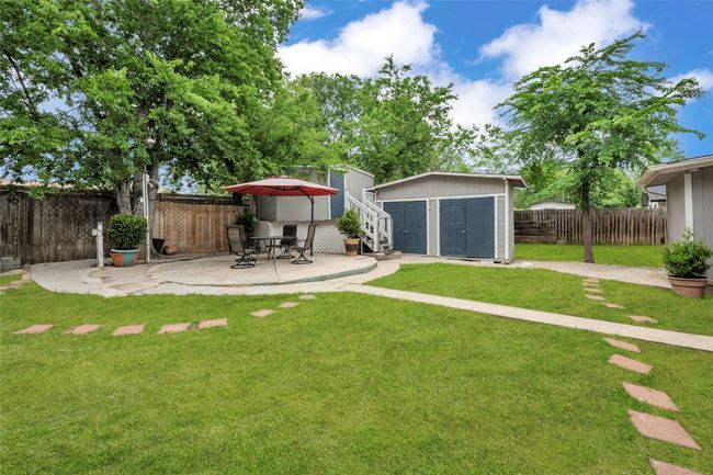 View of yard with a fenced backyard, a storage unit, a patio, and an outbuilding | Image 5