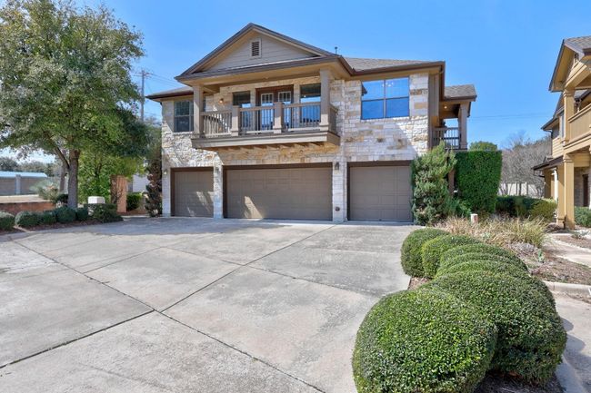 View of front facade featuring a balcony, a garage, stone siding, concrete driveway, and roof with shingles | Image 30
