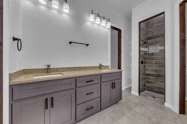 Bathroom with tile patterned flooring, vanity, and a tile shower | Image 19