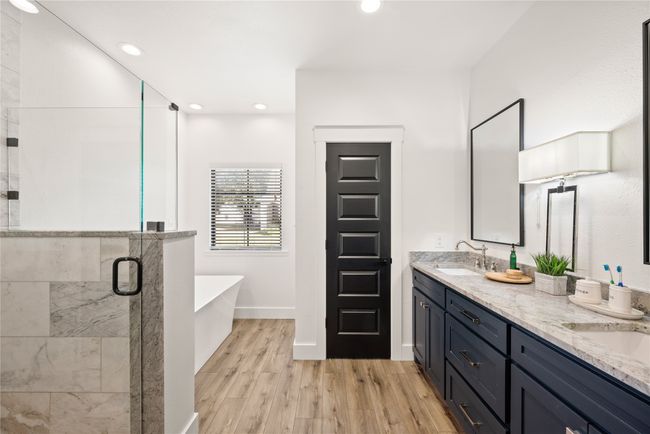 Bathroom with a freestanding tub, double vanity, a stall shower, wood finished floors, and recessed lighting | Image 25