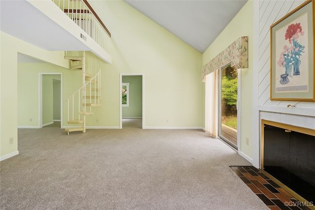 Unfurnished living room with carpet floors, high vaulted ceiling, and stairs | Image 10