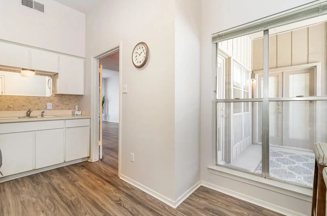 Kitchen with wood finished floors, light countertops, white cabinetry, backsplash, and baseboards | Image 7