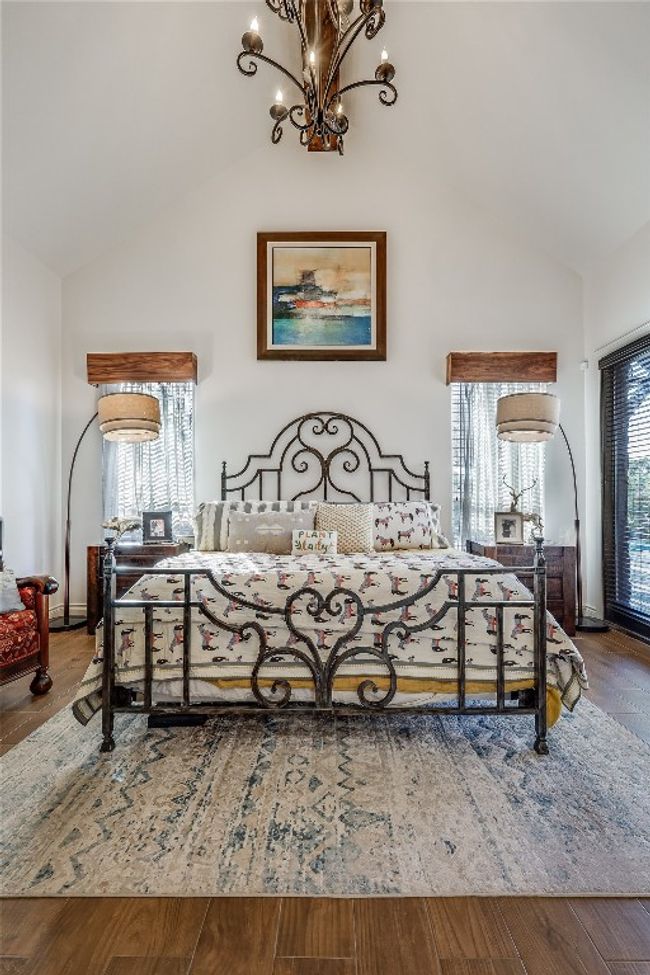Bedroom featuring an inviting chandelier, multiple windows, wood finished floors, and high vaulted ceiling | Image 20