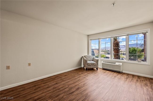 Sitting room with wood finished floors, a wall mounted AC, and baseboards | Image 7