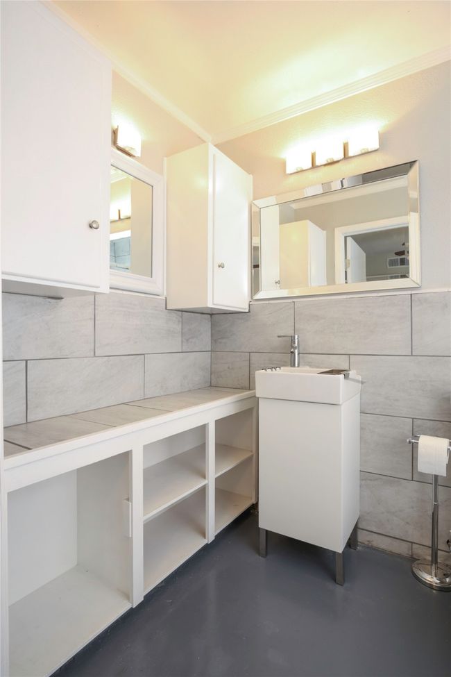 Bathroom featuring tile walls, finished concrete floors, vanity, and tasteful backsplash | Image 19
