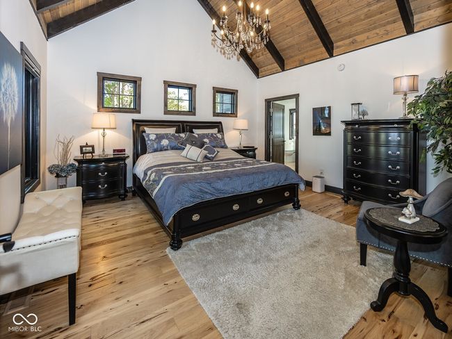 bedroom featuring a chandelier, high vaulted ceiling, wooden ceiling with exposed beams, wood finished floors, and baseboards | Image 18