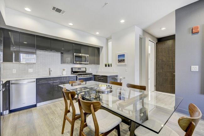 Kitchen with stainless steel appliances, light wood-style floors, light countertops, decorative backsplash, and modern cabinets | Image 7
