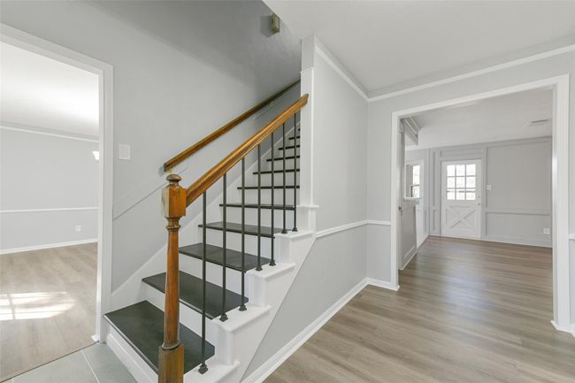 Welcome to a bright and inviting entryway featuring elegant hardwood floors, abundant natural light, and a cozy fireplace flanked by built-in shelving. | Image 4
