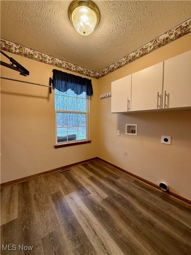 Washroom with a textured ceiling, dark wood-style flooring, hookup for an electric dryer, washer hookup, and cabinet space | Image 15