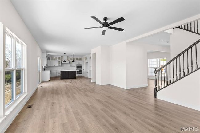 Unfurnished living room featuring light wood-type flooring, stairs, ceiling fan, and recessed lighting | Image 20