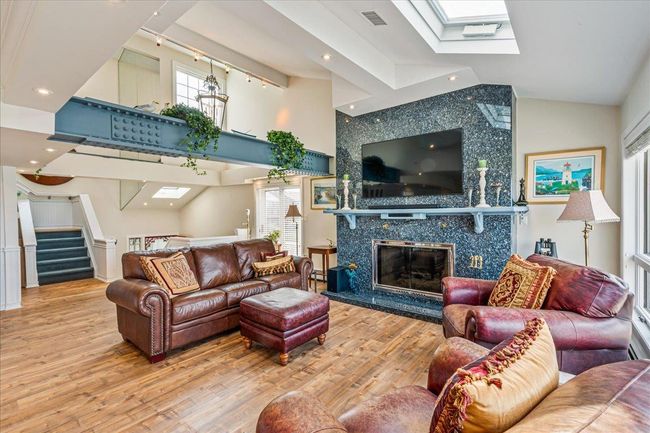 Living area with a skylight, wood finished floors, stairway, a fireplace, and recessed lighting | Image 13