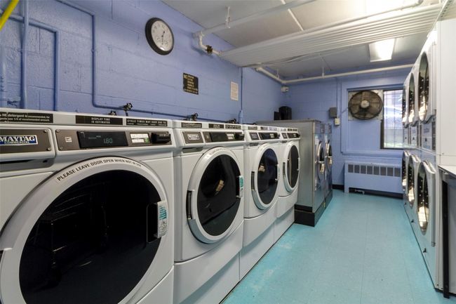 Shared laundry featuring radiator, stacked washer / drying machine, washing machine and clothes dryer, concrete block wall, and light floors | Image 24